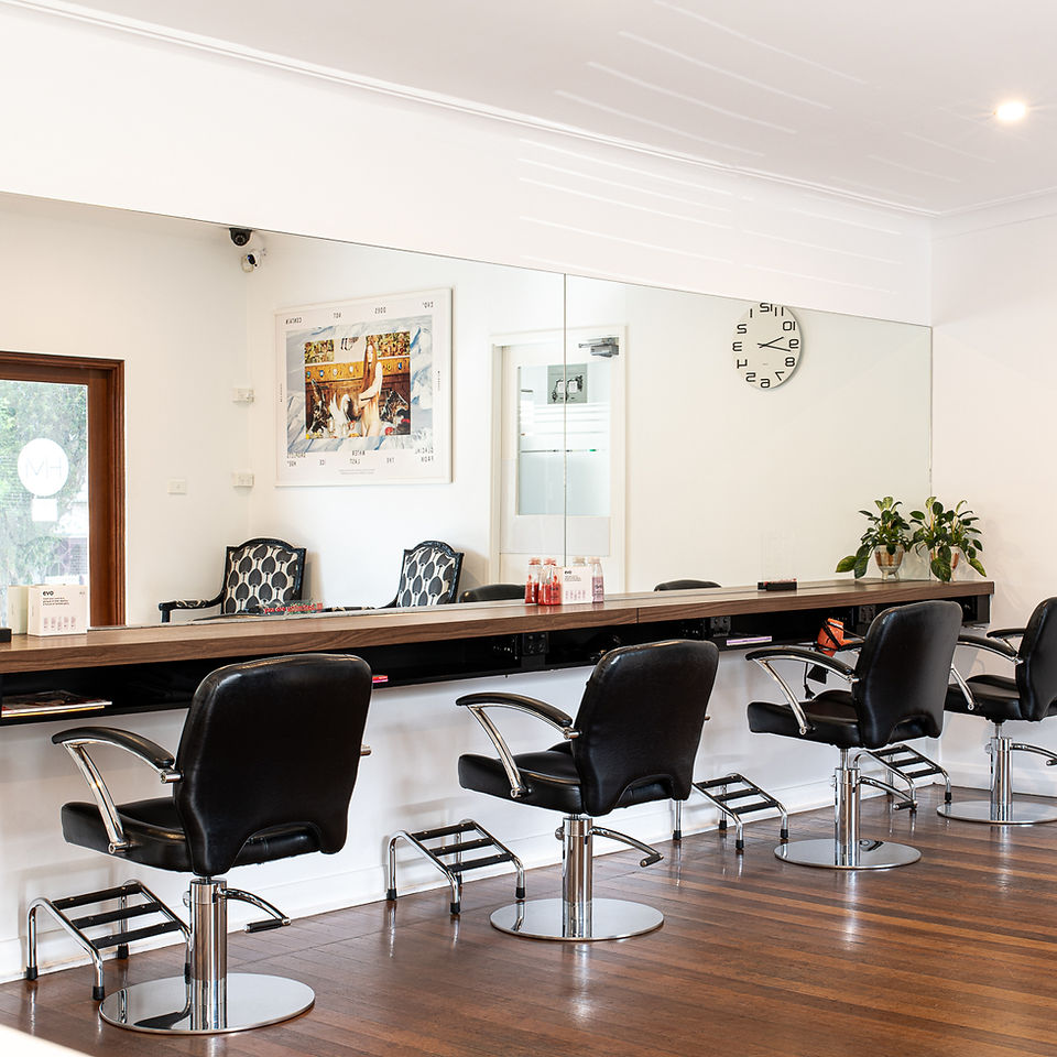 Interior of salon with empty styling chairs and wall-length mirrors