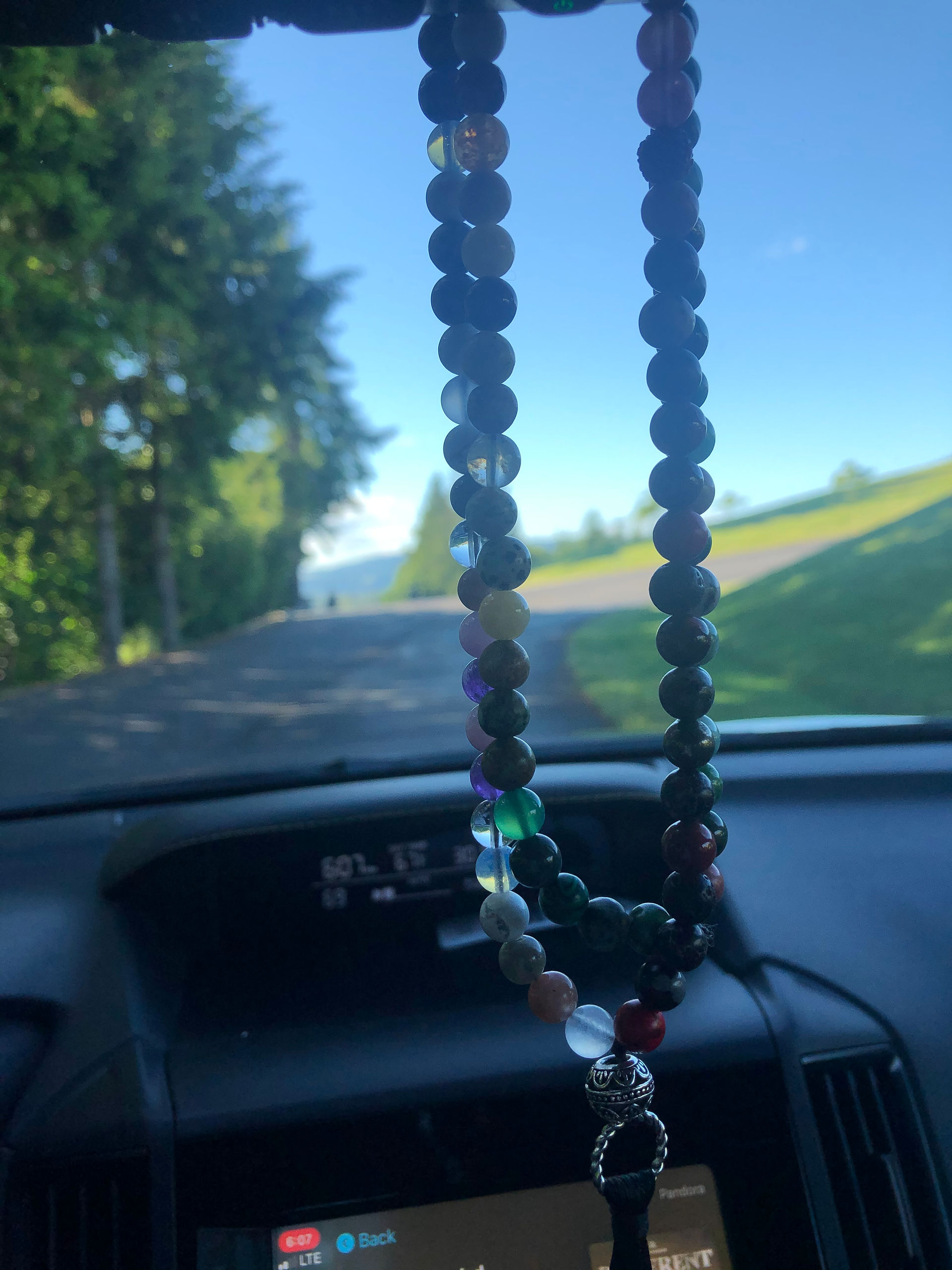 Colorful beads hanging from a rearview mirror in the shade