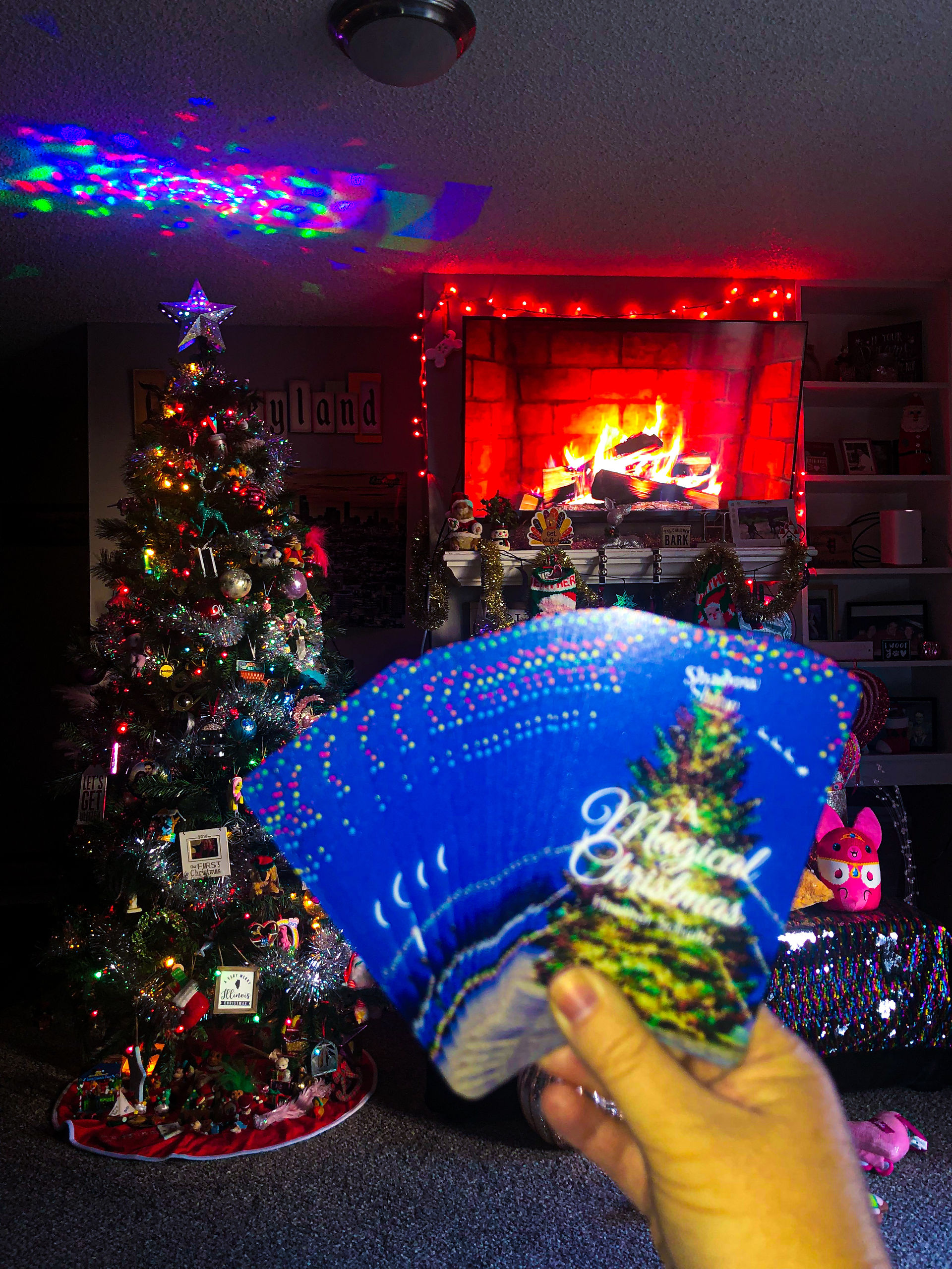 A Magical Christmas Oracle Deck in front of a fireplace and Christmas tree