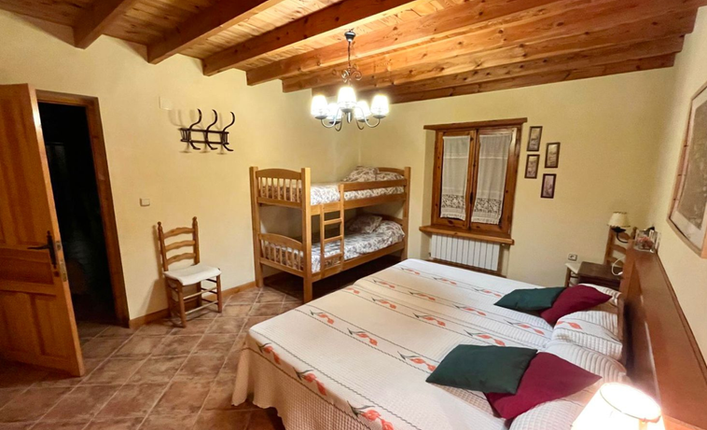 Cozy bedroom with double bed and bunk bed, wooden ceiling beams, and rustic décor in a country villa in Vélez-Blanco