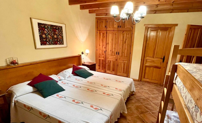 Bright bedroom with double bed, built-in wooden wardrobe, and en suite bathroom in a rustic Andalusian villa in Vélez-Blanco