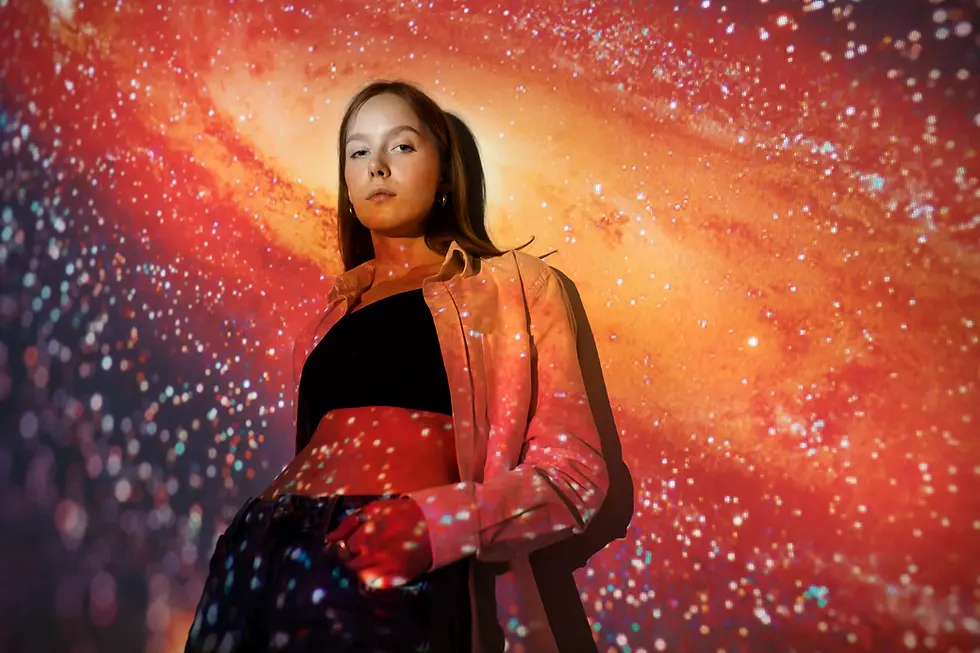 Woman standing before a galaxy projection.
