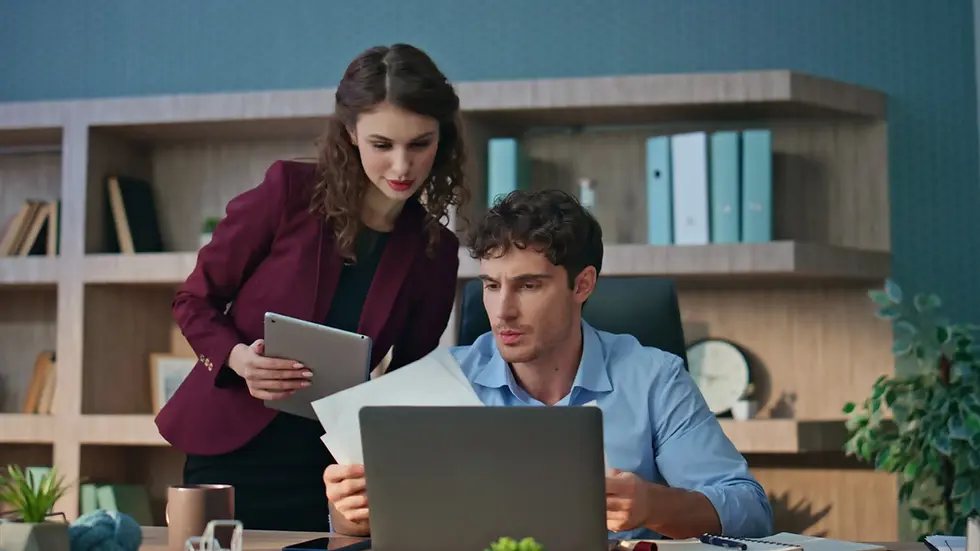 Two colleagues reviewing documents and laptop in an office