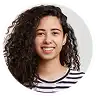 Smiling young woman with long dark curly hair wearing a striped shirt.