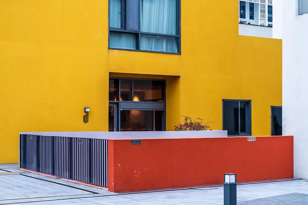 Modern building exterior with yellow and orange walls, glass door and window.