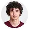 Smiling young man with dark curly hair in a headshot.