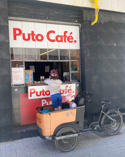 Kids in helmets ordering from a cargo bike at Puto Café, Valencia.