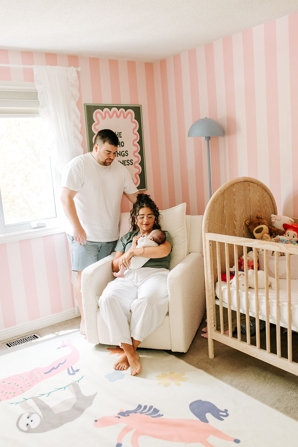 Newborn family photography in Guelph, Ontario capturing a quiet moment with baby in a nursery featuring hand-painted striped walls