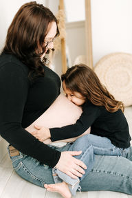 Studio maternity session in Guelph, Ontario featuring mom and her daughter in coordinated outfits, celebrating their upcoming addition.