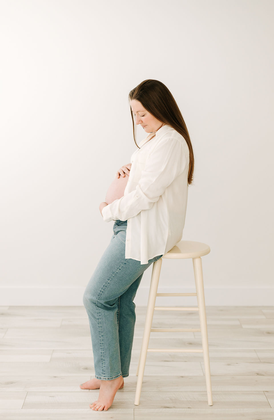 Mom-to-be in white bralette, white button-up shirt, and jeans during her maternity session at Elle Chic Photography Studio, Guelph