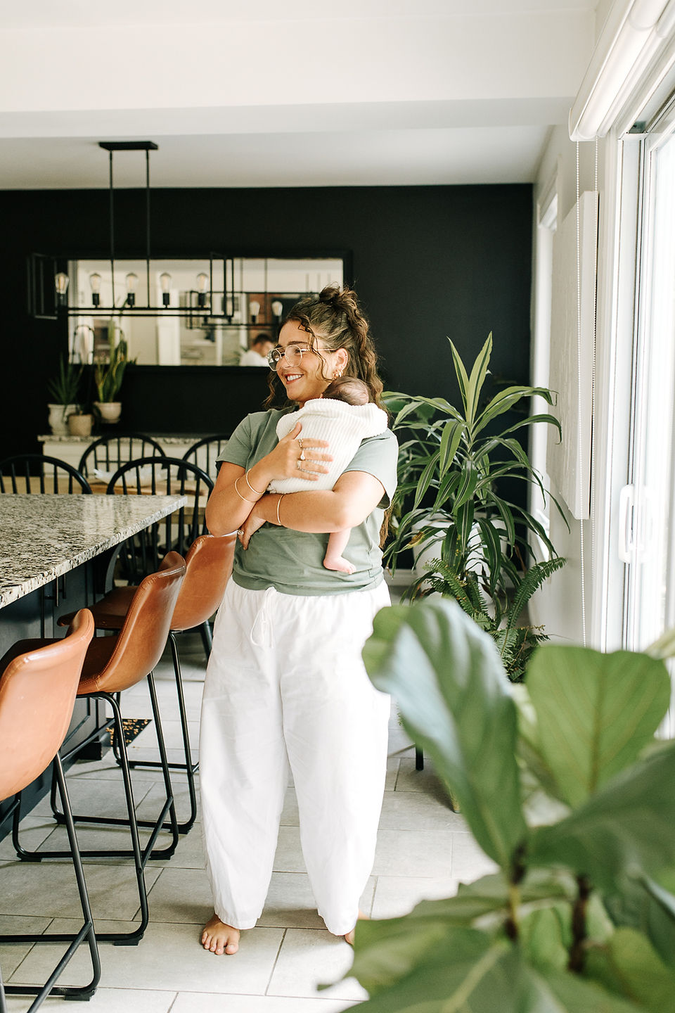 Guelph, Ontario in-home newborn photography capturing mom cuddling her newborn baby in a bright kitchen and dining area