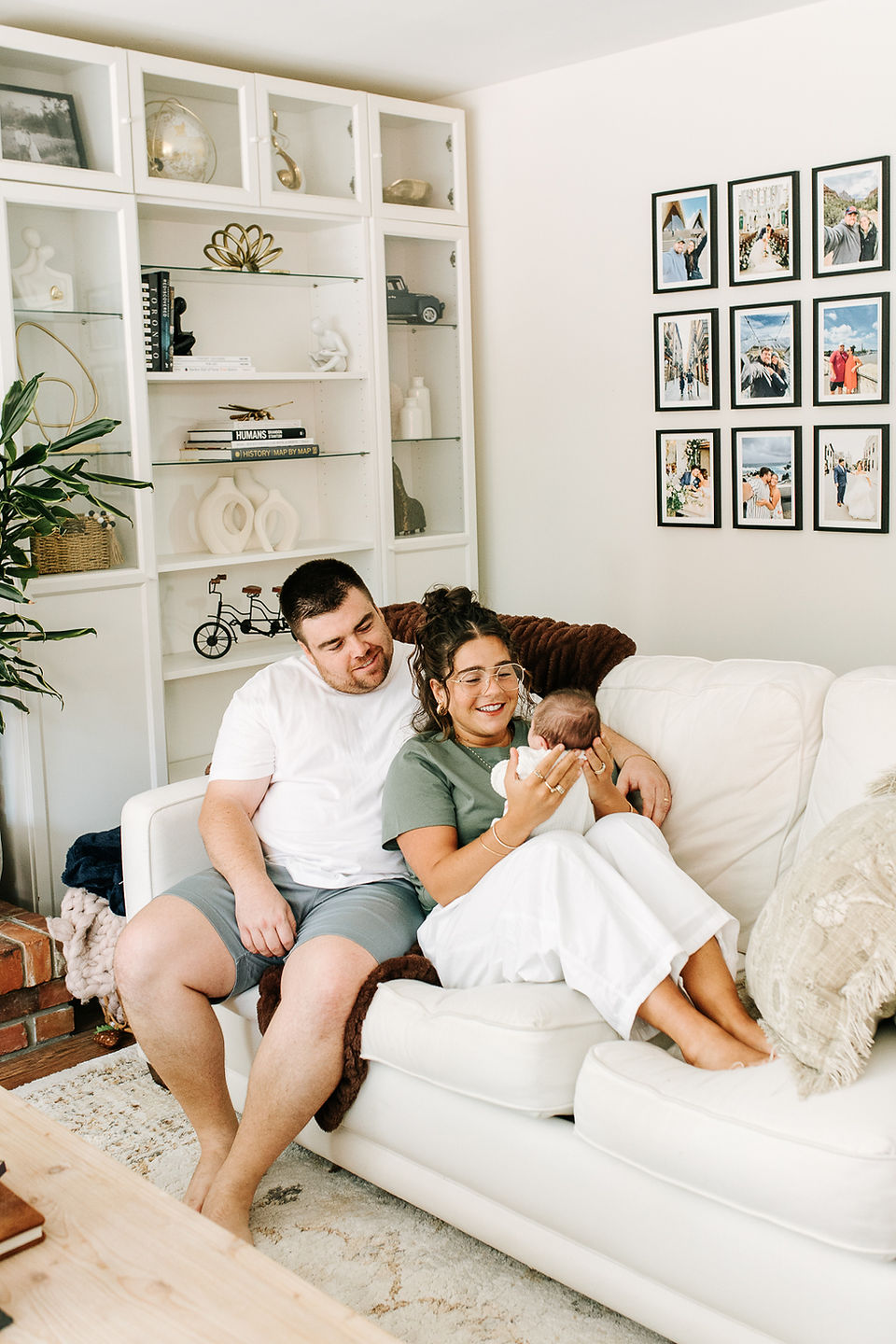In-home newborn session in Guelph, Ontario featuring parents cuddling their newborn baby together on a light-colored couch