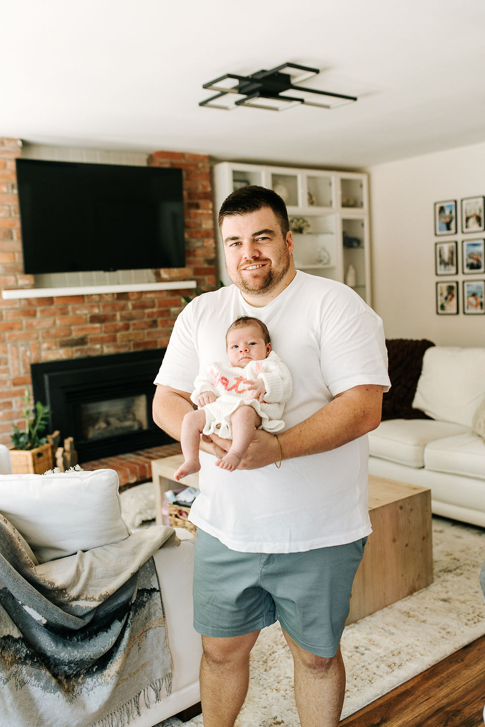 In-home newborn session in Guelph, Ontario featuring dad holding his newborn baby in a bright living room