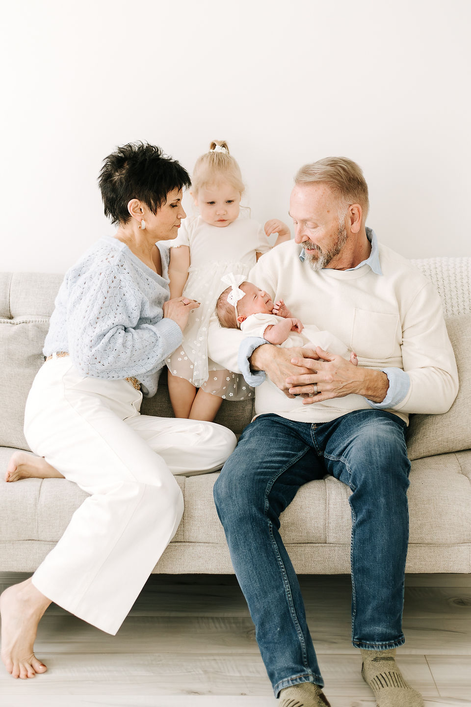 Grandparents with toddler and newborn baby during a newborn session in Guelph, Ontario in a soft studio portrait