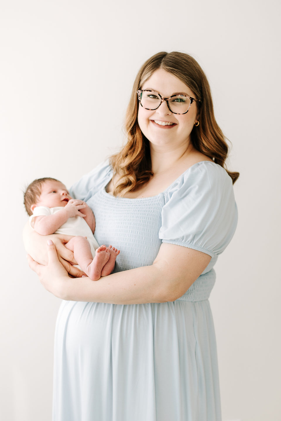 Mom holding newborn baby during a newborn session in Guelph, Ontario in a soft and natural studio portrait