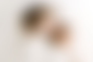 Newborn session in Guelph, Ontario capturing sister affectionately interacting with newborn baby in a bright, minimalist studio portrait