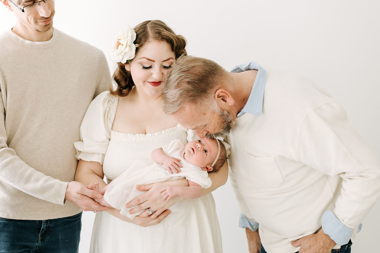 Grandma and grandpa with parents and newborn baby during a newborn session in Guelph, Ontario in a clean studio setting