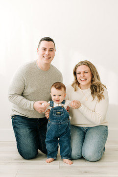 Parents and baby boy together in a first birthday family photoshoot at a photography studio.