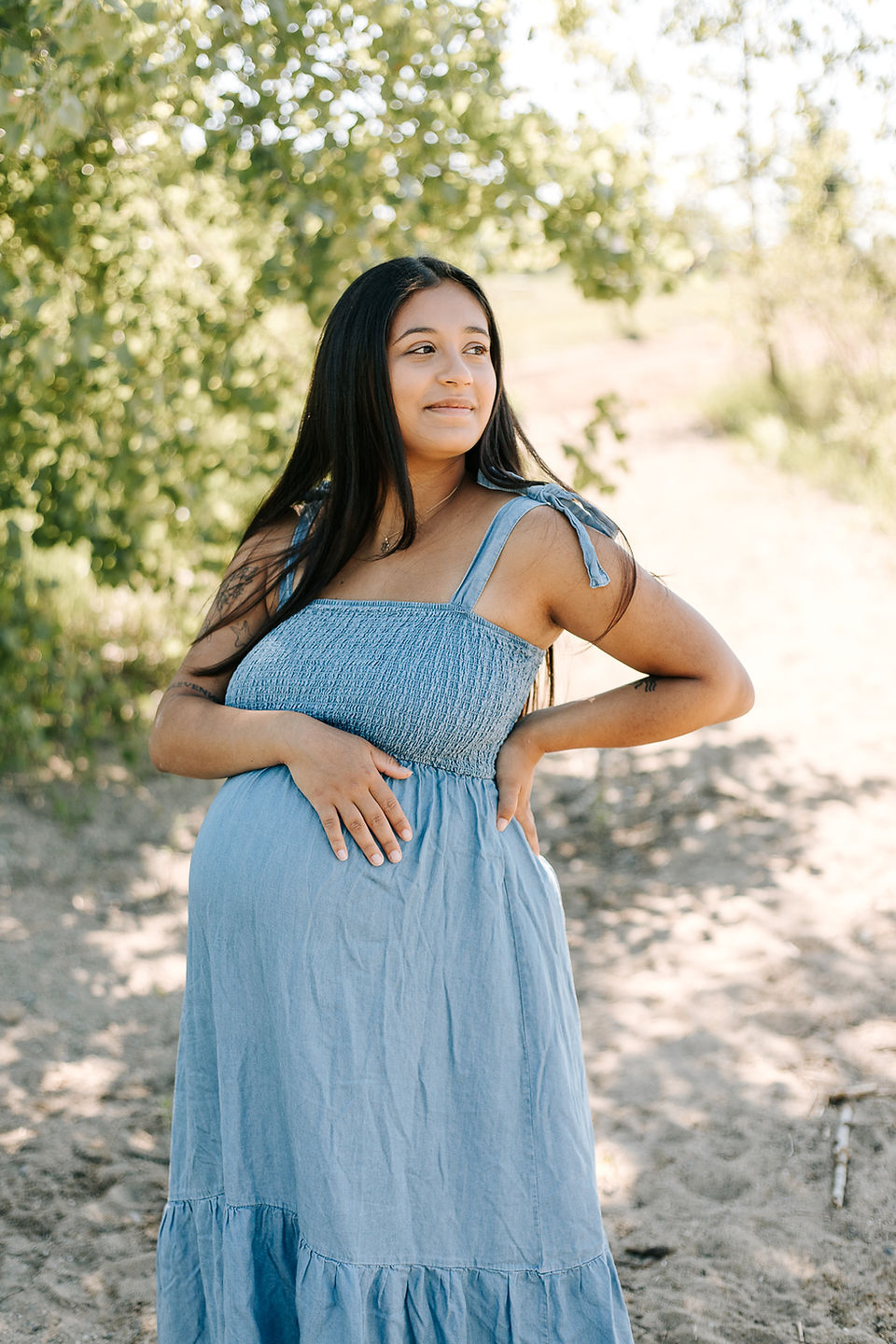 Beach maternity session in Guelph, Ontario featuring a glowing mom-to-be in a blue maternity dress surrounded by lush greenery