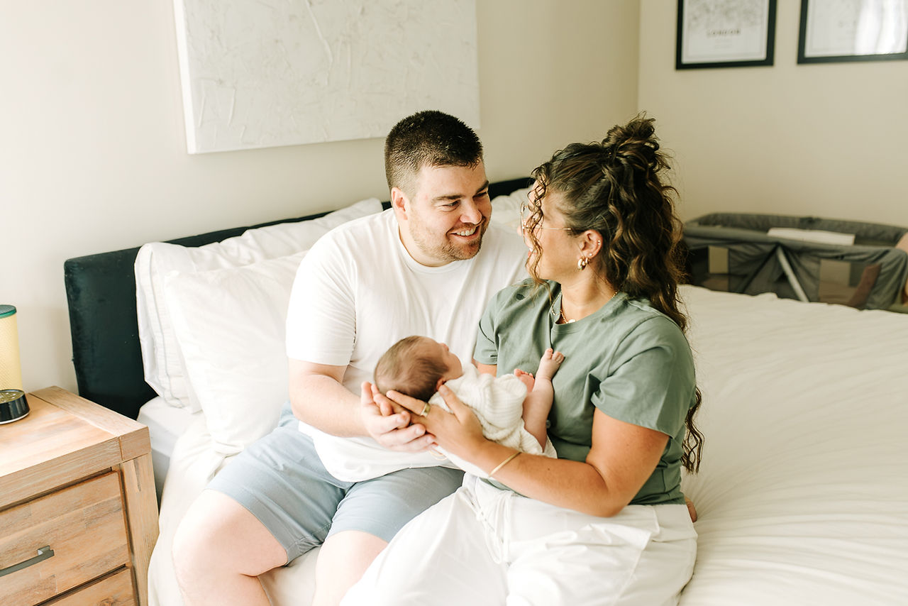 Guelph, Ontario newborn photography capturing parents sharing a loving moment with their newborn in the bedroom