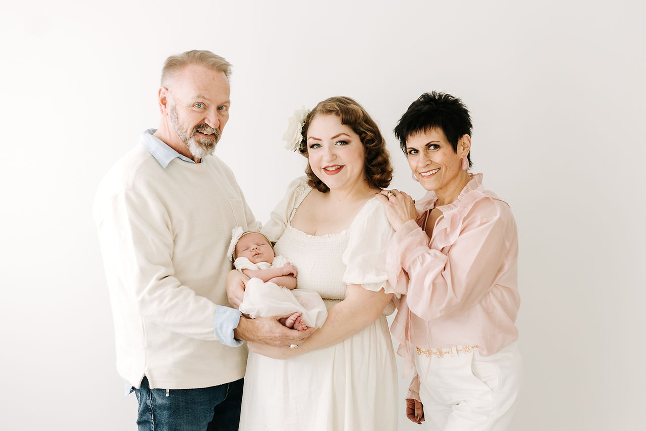 Grandma and grandpa with parents and newborn baby during a newborn session in Guelph, Ontario in a clean studio setting