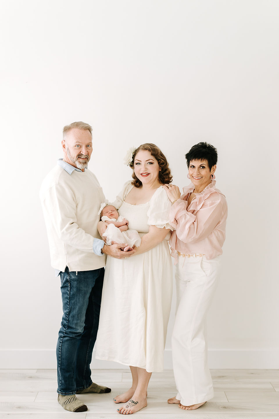 Grandma and grandpa with parents and newborn baby during a newborn session in Guelph, Ontario in a clean studio setting