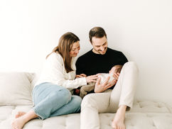 Newborn session in Guelph, Ontario featuring family of three with baby wrapped in white blanket in a soft, natural studio portrait