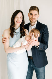 Family newborn session in Guelph, Ontario with mom in light blue dress and dad in blazer holding sleeping newborn baby
