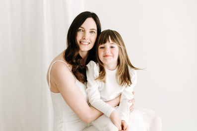 Mother and young daughter portrait during a newborn session in Guelph, Ontario wearing white outfits in a bright minimalist studio setting