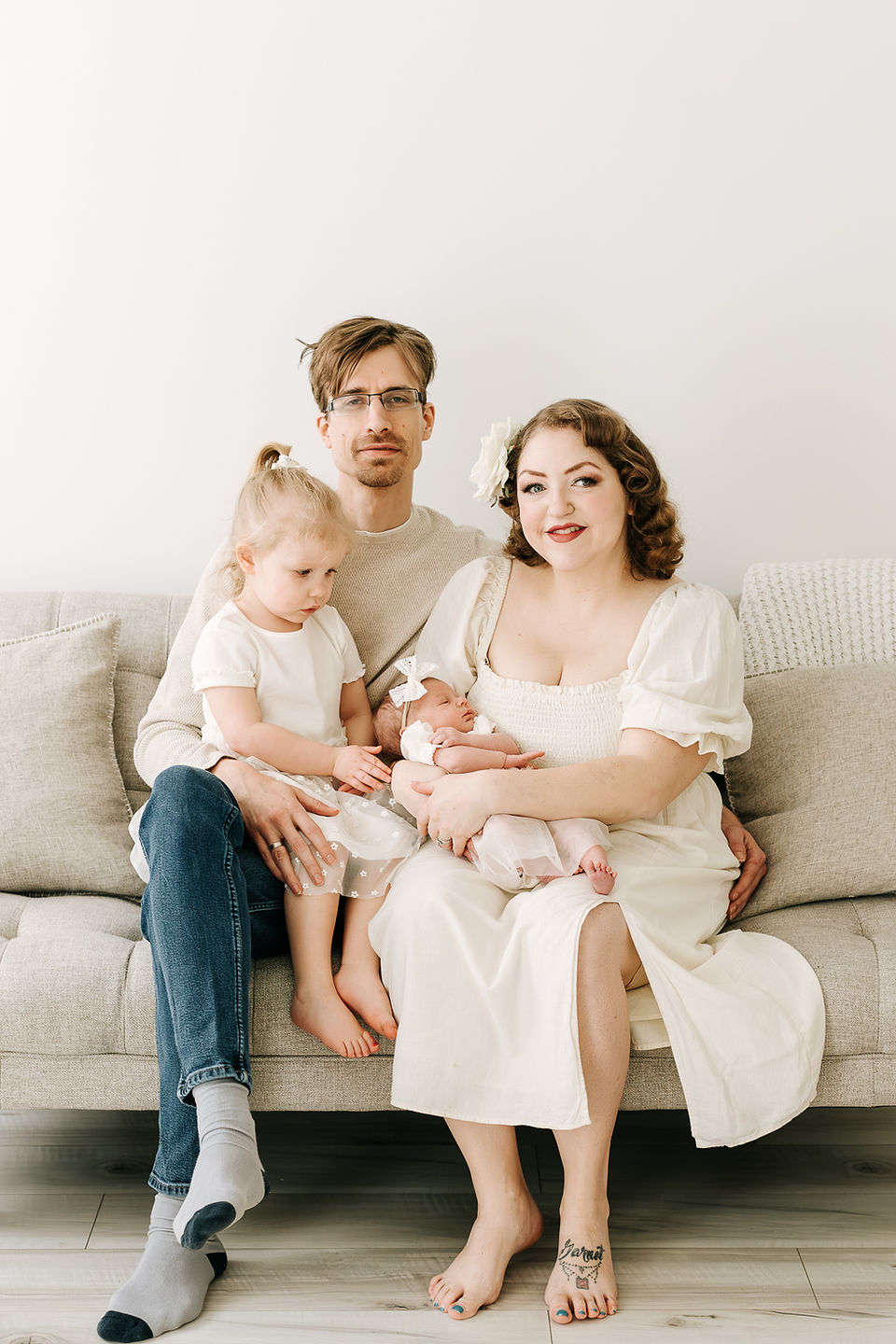 Mom, dad, toddler girl, and newborn baby during a newborn session in Guelph, Ontario captured in a clean, natural studio setting