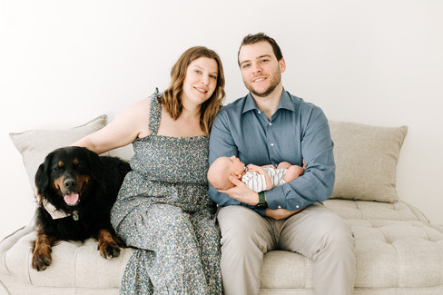 Studio newborn session in Guelph, Ontario featuring parents, newborn baby, and family dog in a bright, minimalist studio portrait