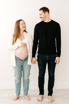 Expecting couple holding hands and smiling in a maternity session at Elle Chic Photography Studio, Guelph
