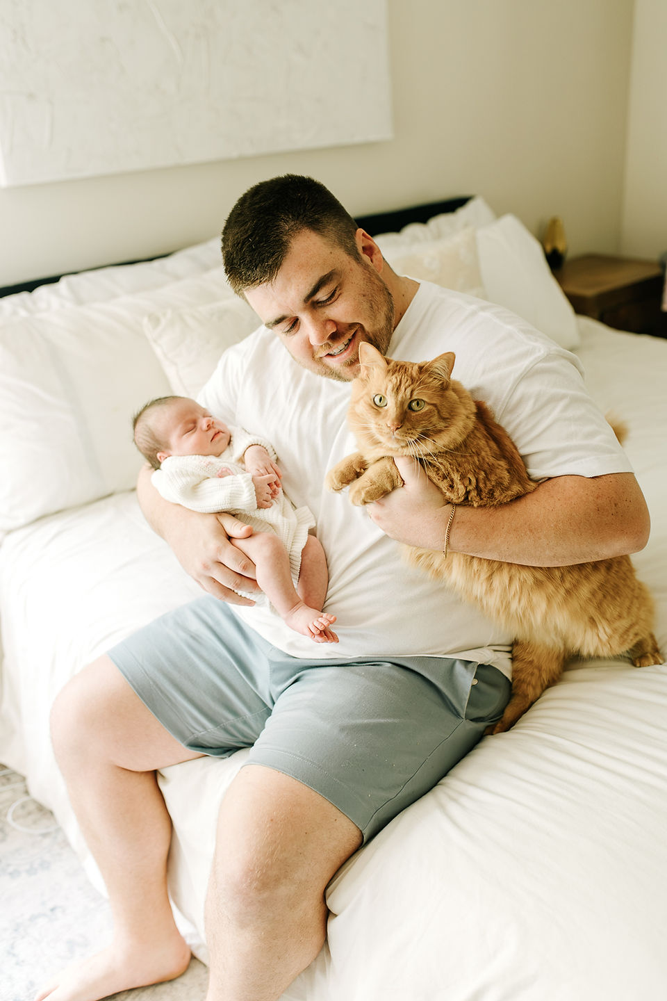 In-home newborn session in Guelph, Ontario capturing a sweet moment between dad, his sleeping newborn, and the family cat