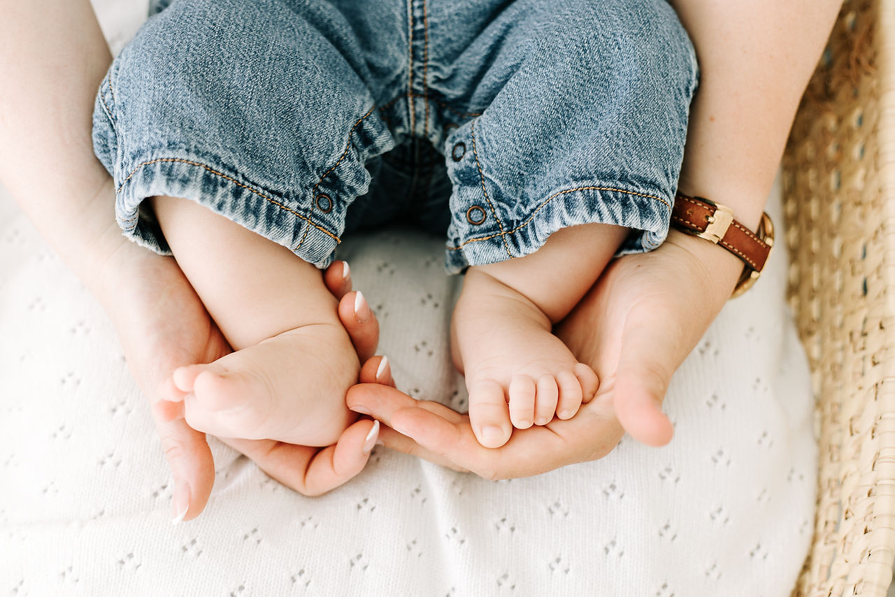 Studio milestone session in Guelph, Ontario showcasing baby's tiny feet resting in a parent's hands during a 3 month session