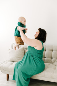 Mother holding baby during a milestone session in Guelph, Ontario in a bright studio setting with soft neutral styling