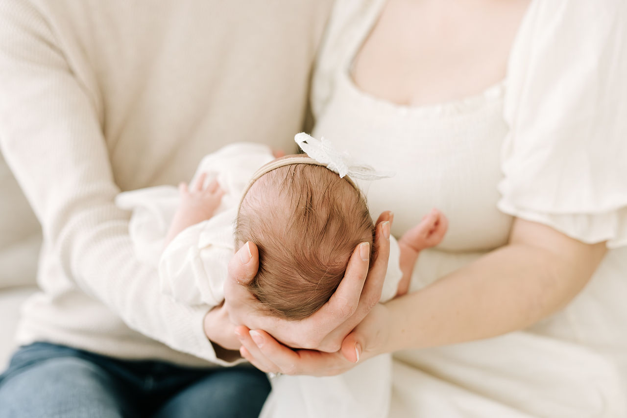 Mom and dad with newborn baby during a newborn session in Guelph, Ontario captured in a soft studio portrait