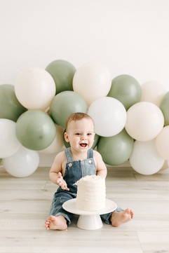 Baby smiling while enjoying cake during a From Maternity to Milestones milestone session in Guelph, Ontario