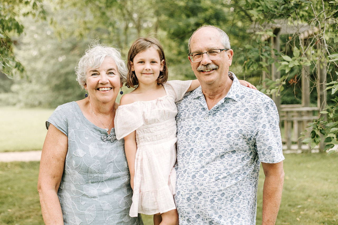 Grandparents holding their granddaughter during an extended family session at The Guelph Arboretum in Guelph, Ontario.