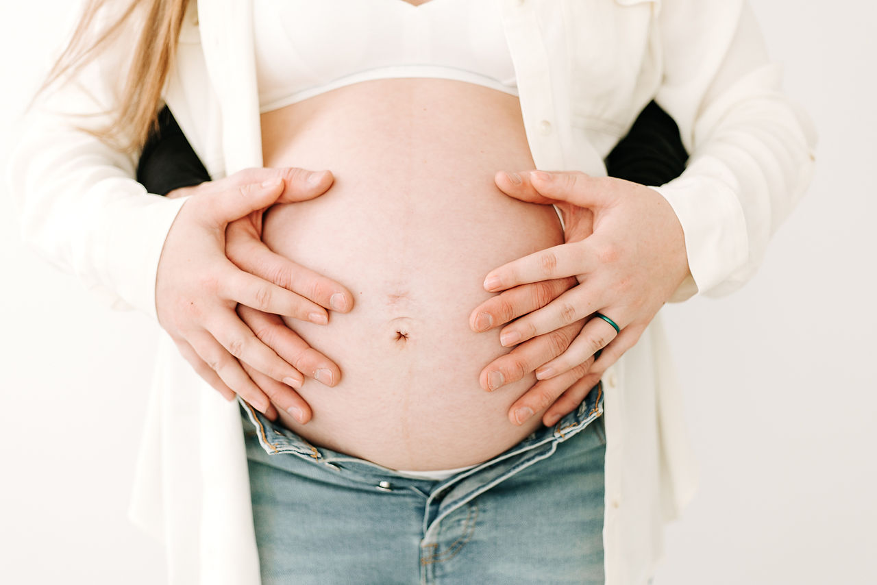 Expecting couple holding the baby bump in a maternity session at Elle Chic Photography Studio, Guelph