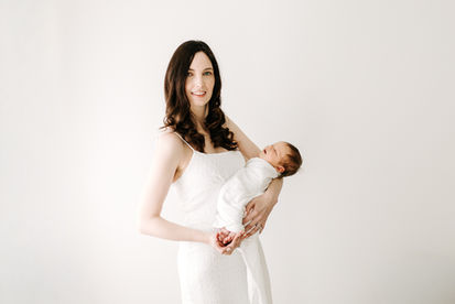 Newborn session in Guelph, Ontario featuring mother holding swaddled newborn baby in a bright, minimal studio portrait