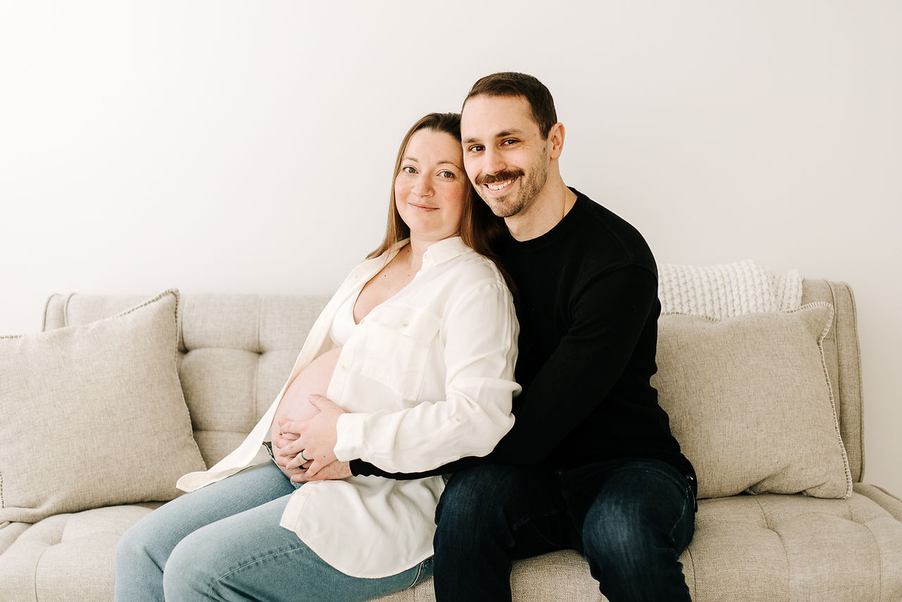 Expecting couple holding hands and smiling in a maternity session at Elle Chic Photography Studio, Guelph