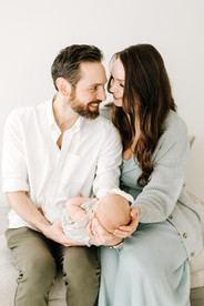 Mom and dad holding newborn baby during a newborn session in Guelph, Ontario with soft studio lighting