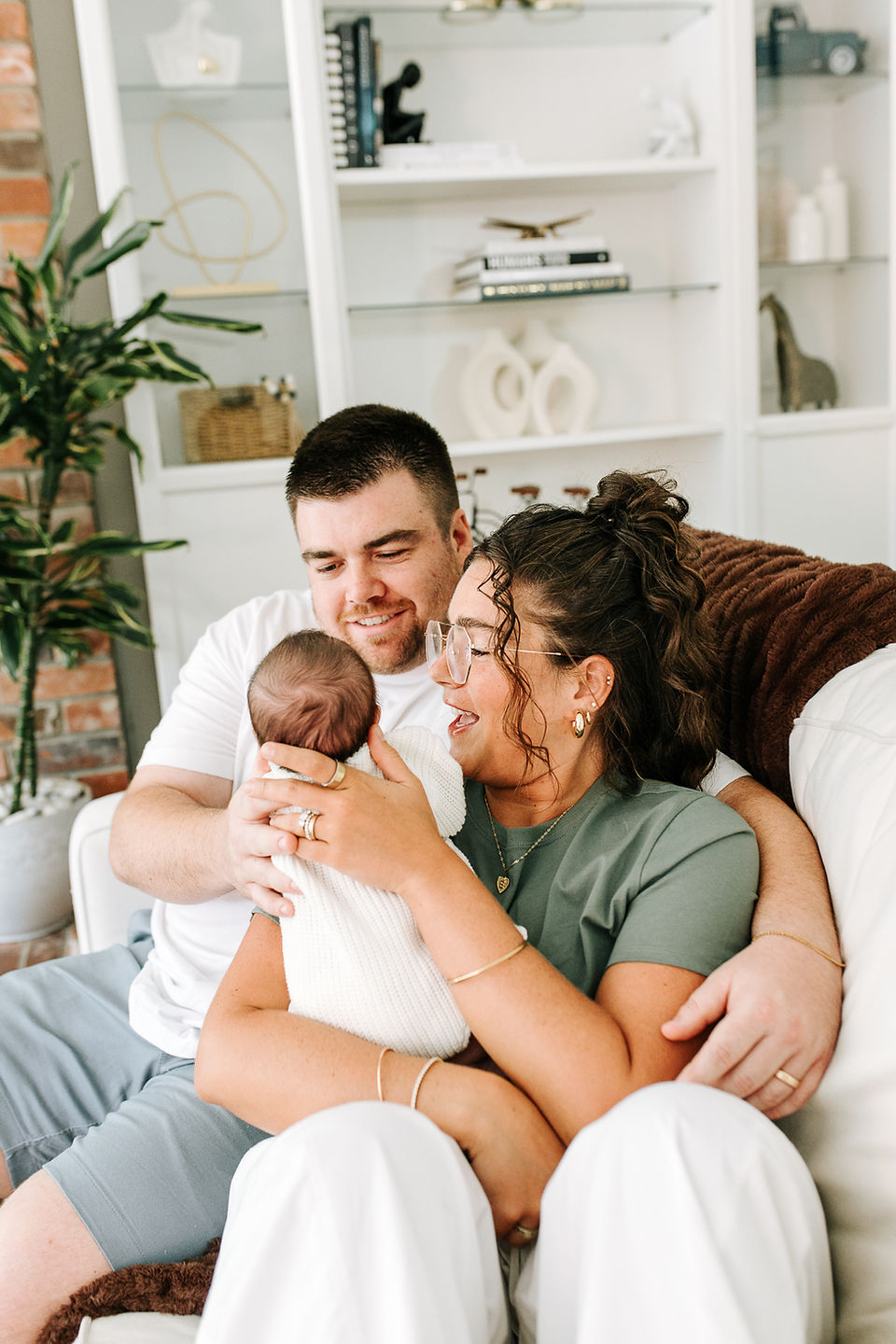 In-home newborn session in Guelph, Ontario featuring a swaddled newborn and parents enjoying a tender family moment at home