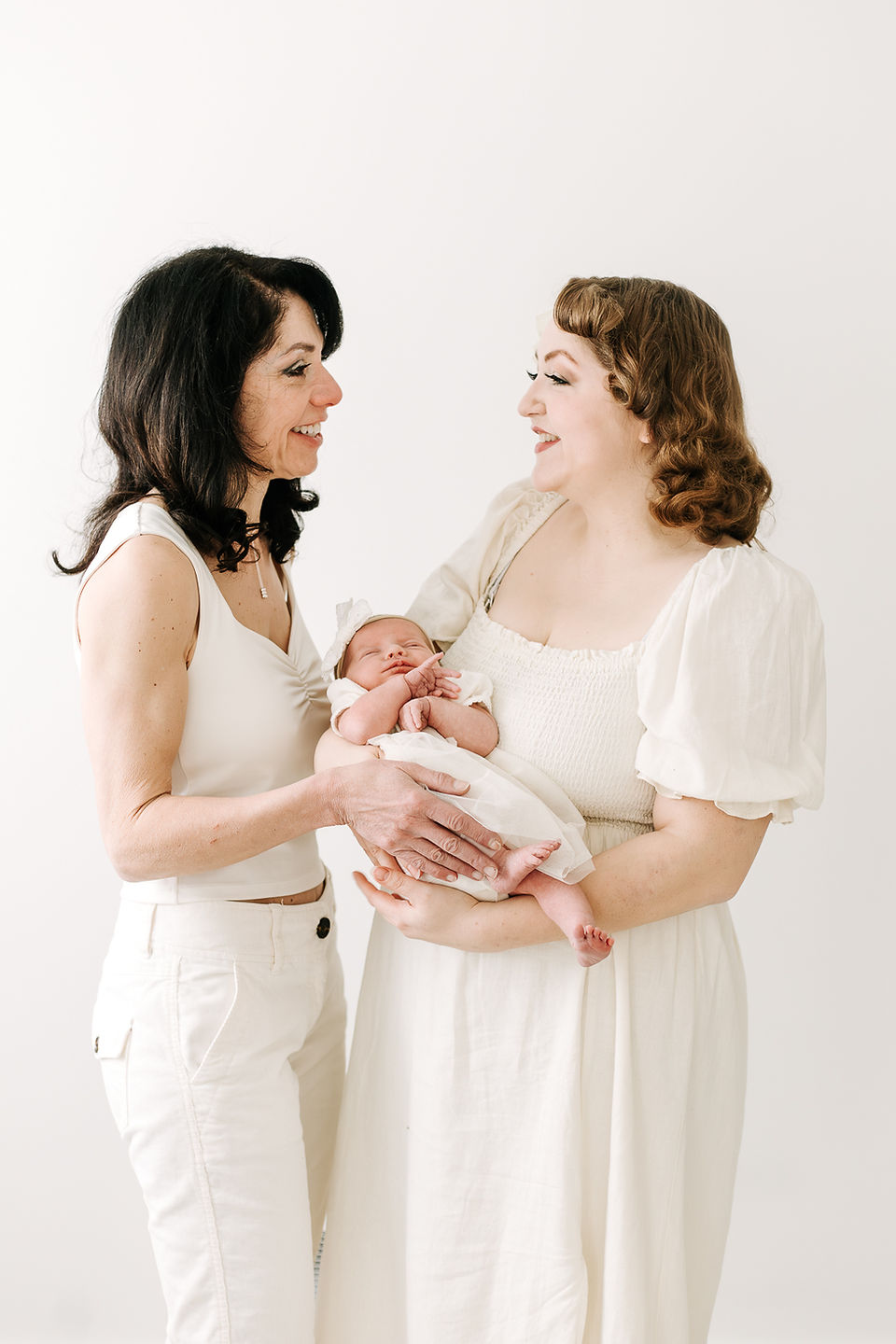 Auntie and Mom with the newborn baby during a newborn session in Guelph, Ontario in a soft studio portrait