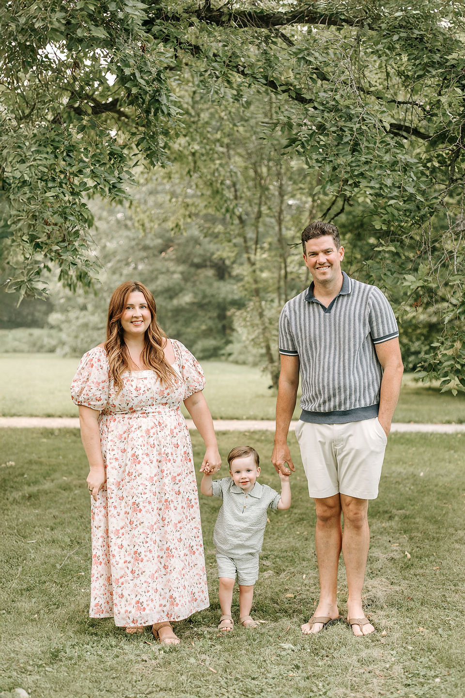 Parents and young toddler posing together on a grassy lawn during a family photography session in Guelph, Ontario.
