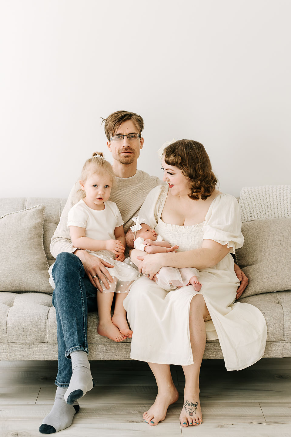 Family of four with toddler and newborn baby during a newborn session in Guelph, Ontario in a soft studio portrait