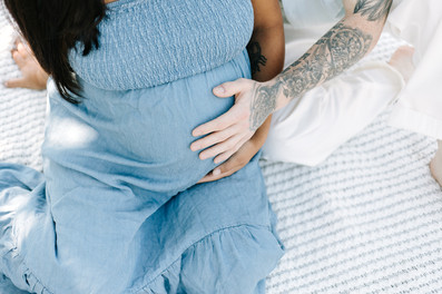 Maternity session in Guelph, Ontario featuring a close-up of expecting parents' hands resting on mom's baby bump at Guelph Lake Conservation Area