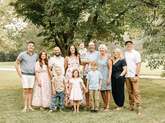 Extended family of eleven posing together outdoors at The Guelph Arboretum in Guelph, Ontario, with grandparents, adult children, spouses, and grandchildren.