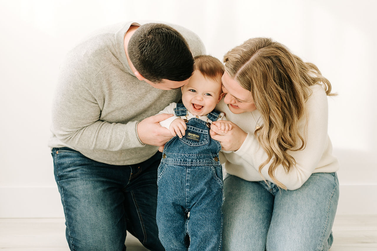 Parents and baby boy together in a first birthday family photoshoot at Guelph photography studio.