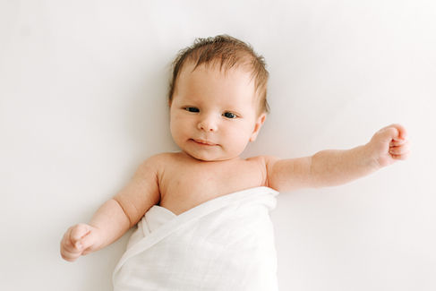 Newborn session in Guelph, Ontario capturing baby with dark hair and blue eyes looking at camera in a soft, minimal studio portrait